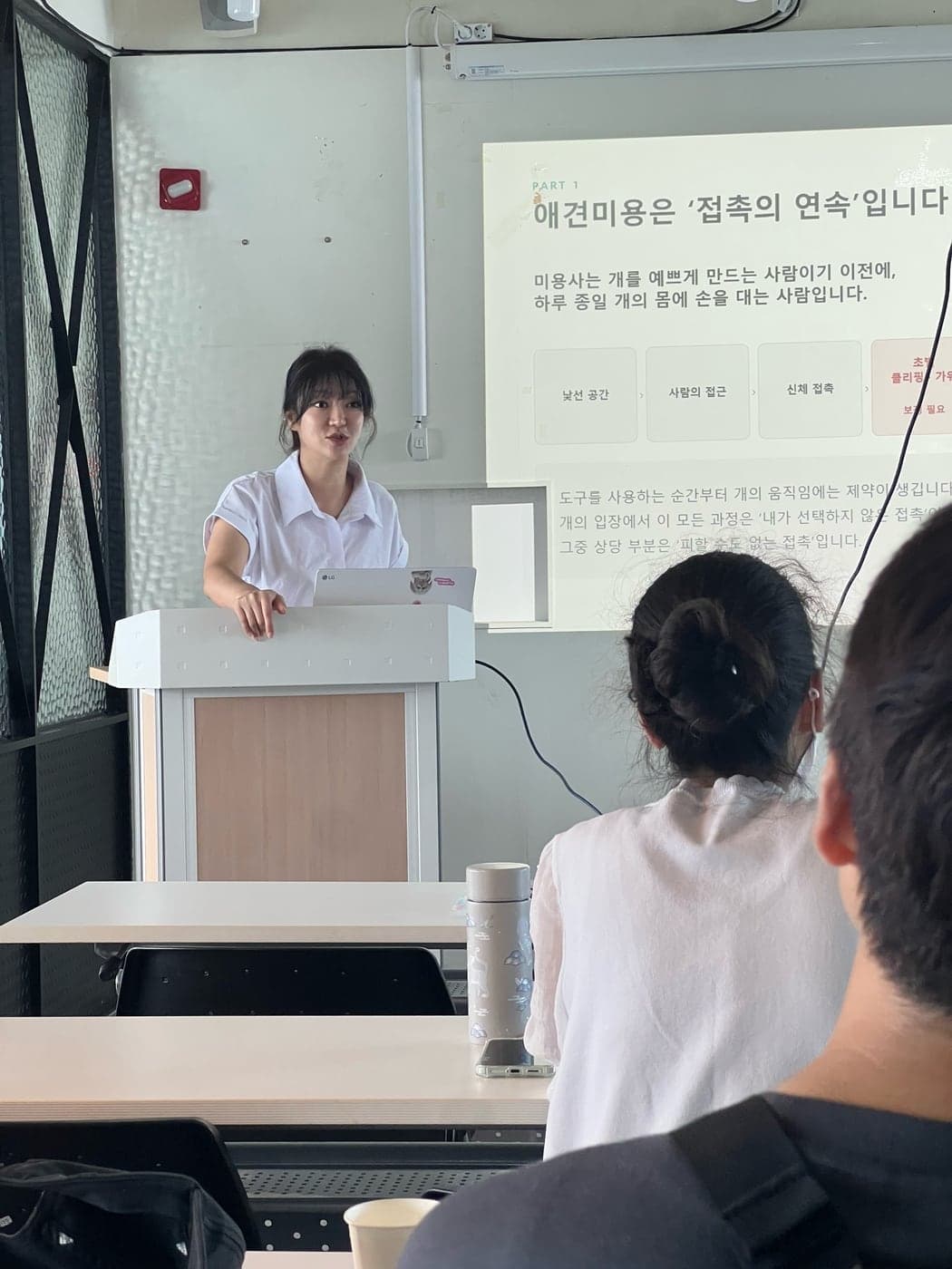 ‘애견미용은 접촉의 연속입니다’라는 슬라이드 앞에서 강연하는 전효정 대표